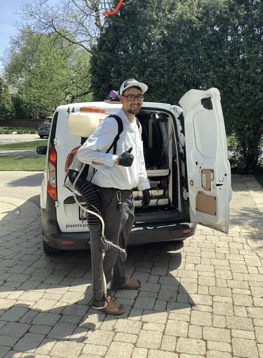 Pointe Pest Control technician with pest control spray on his back standing in front of a pointe pest control truck